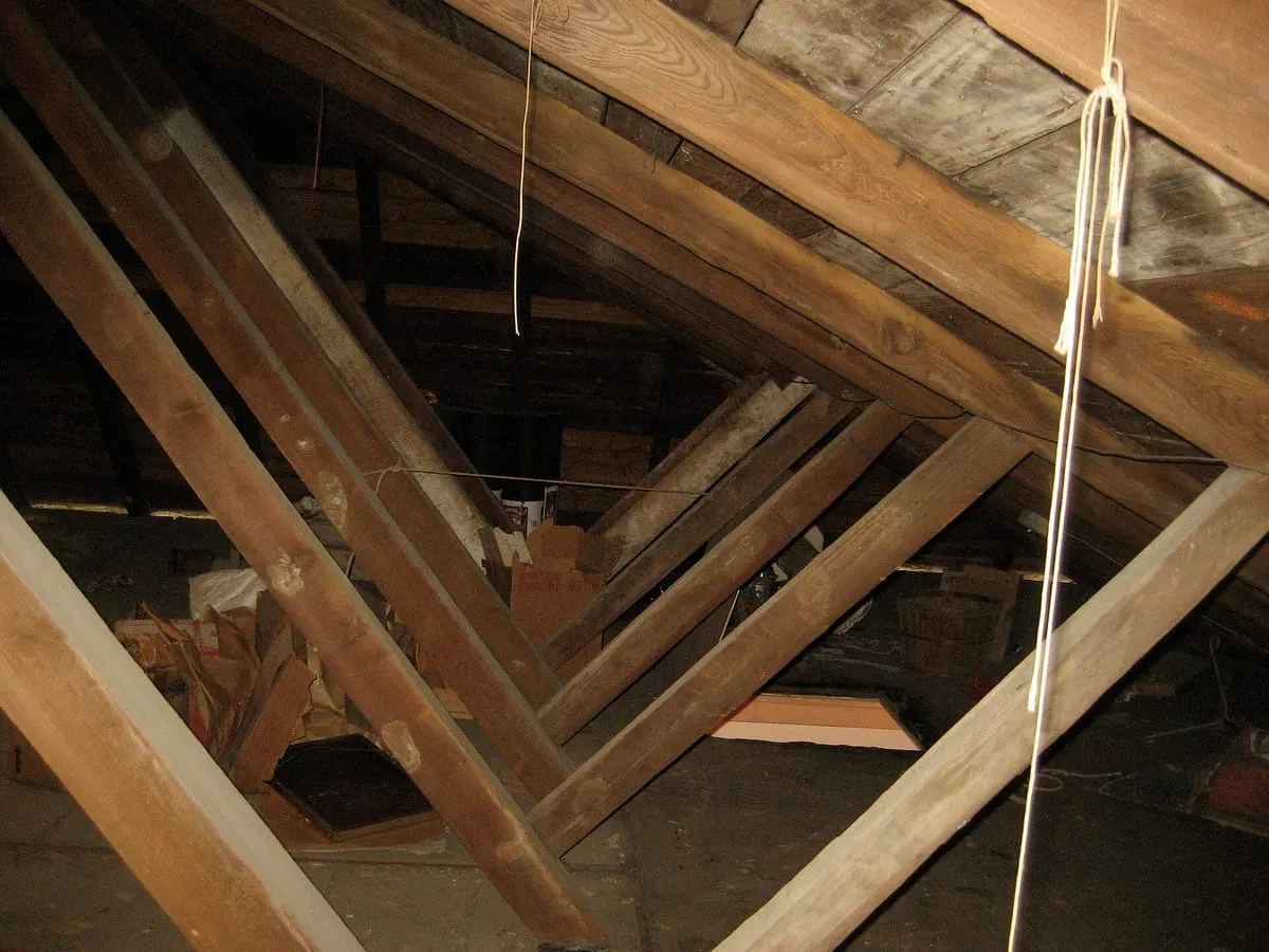 Wooden rafters, collar ties and roof boards inside a dim attic