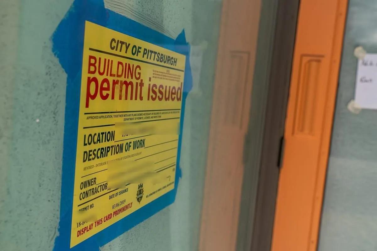 Yellow building permit issued card taped inside a window