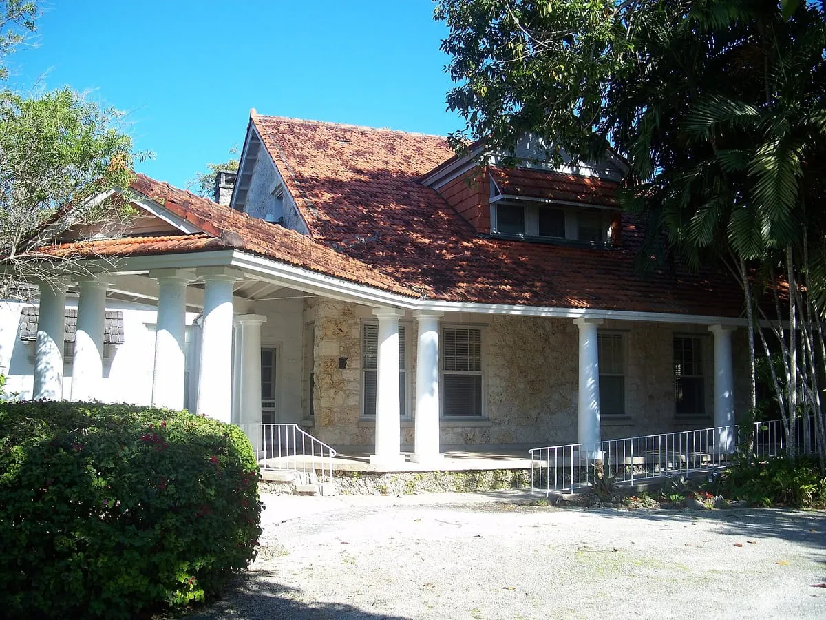 House with a red clay tile roof, white columns and a covered porch