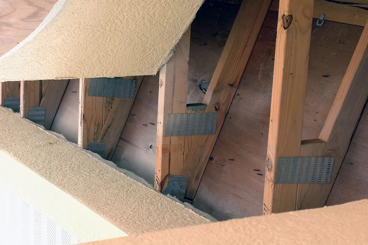 Metal hurricane straps and truss plates where wooden roof trusses rest on a wall