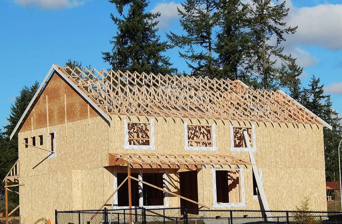 House under construction with wood roof trusses set above OSB-sheathed walls