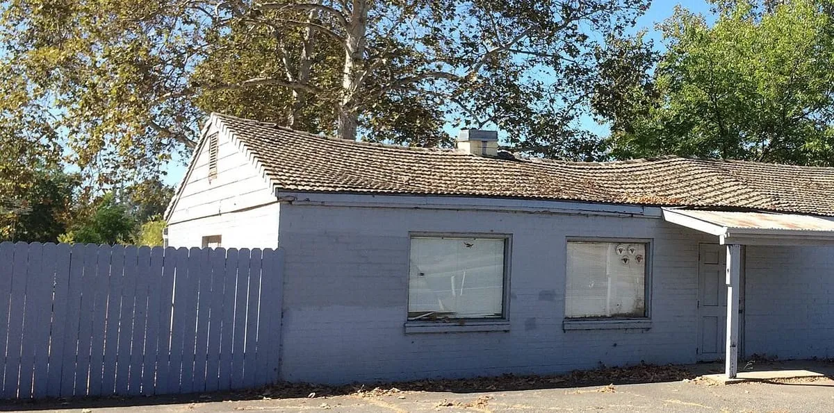 Old single-story building with a concrete tile roof dipping along the ridge