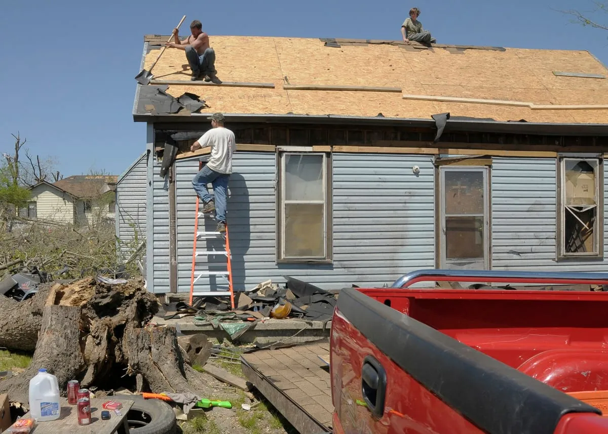 People working on a roof stripped to bare decking, with torn shingles at the eave