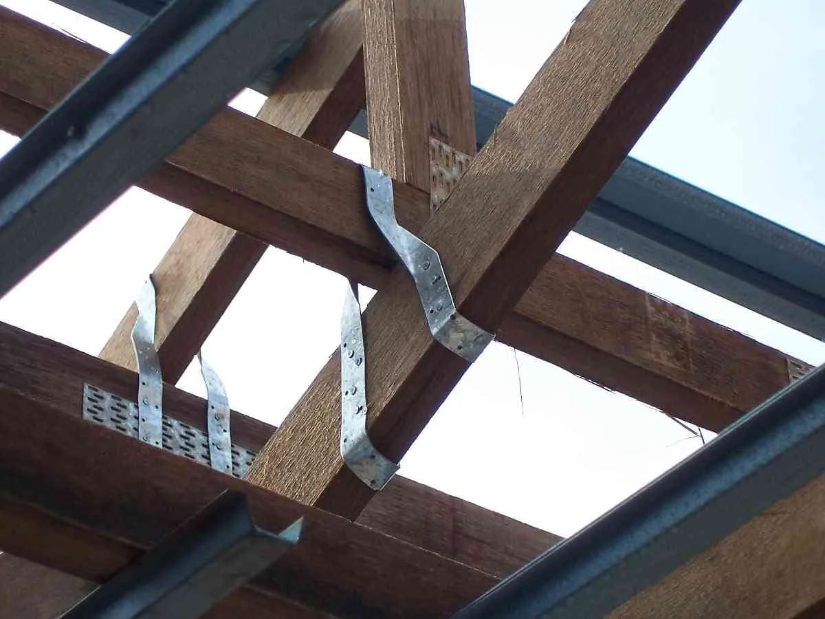 Metal twist straps fastening wooden roof trusses to the framing below them