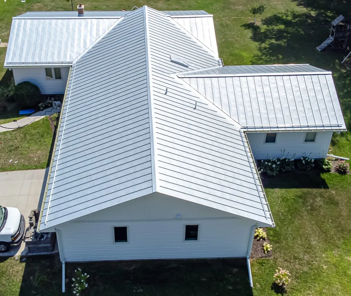 Aerial view of a single-story house with a white standing seam metal roof